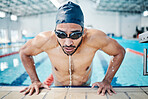 Tired, breathing and man swimming for fitness, training and race in a stadium pool. Strong, sports and face of an athlete swimmer doing cardio in the water for a workout, sport and competition