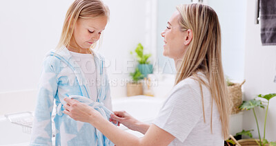 Buy stock photo Girl, mother and bathrobe in a bathroom for cleaning, wellness and hygiene in their home together. Children, washing and woman help child with gown after shower, bond and relax while talking