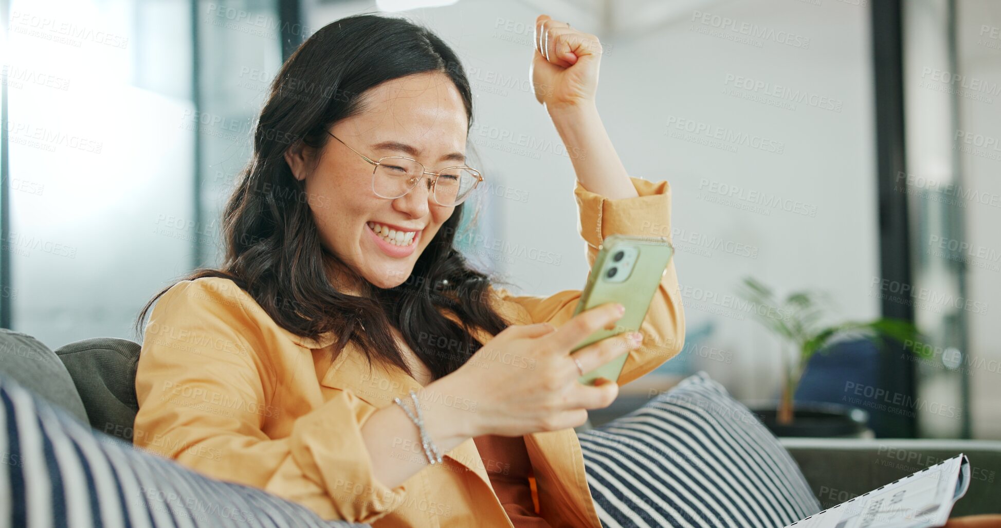 Buy stock photo Business woman, phone and fist celebration for success, goal or profit in trading, fintech and excited on sofa. Asian investor, smartphone and winner with smile, bonus or prize in online competition