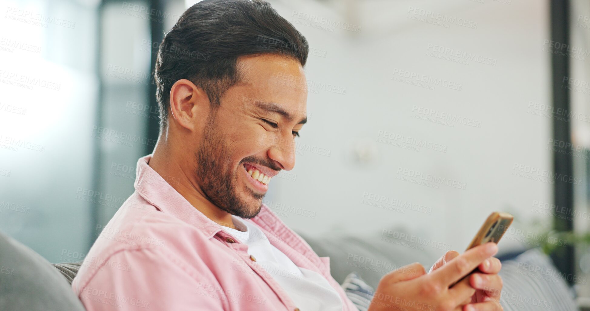 Buy stock photo Phone, smile and a man laughing at a meme on the sofa of his living room at home to relax closeup. Face, social media and funny with a happy young person typing or reading a mobile text message