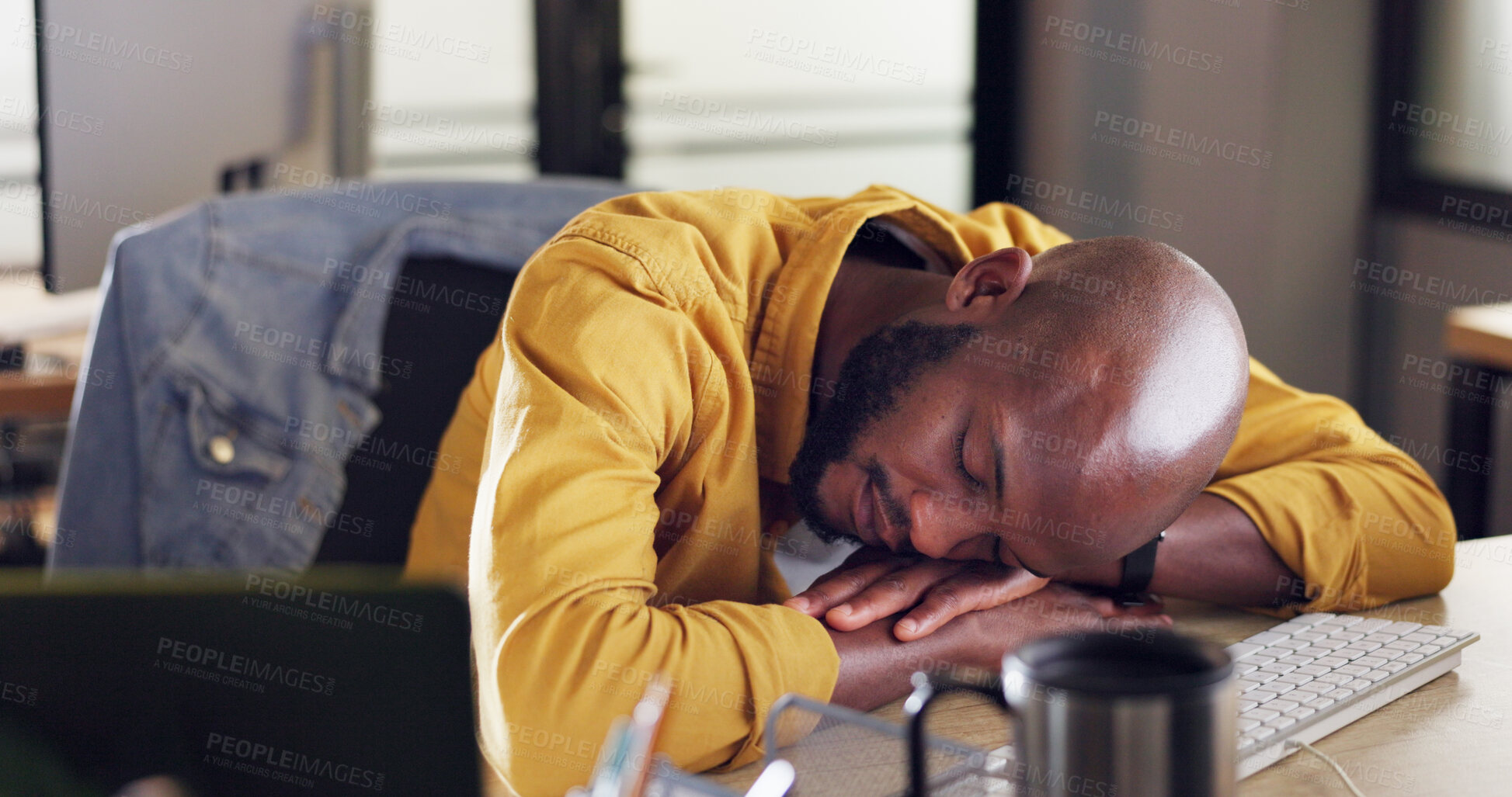 Buy stock photo Burnout, sleeping and tired black man in the office with fatigue for working overtime on project. Exhausted, overworked and young African male designer taking a nap on his desk in the workplace.