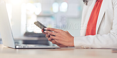Hands browsing online holding a phone with manicured nails. Closeup of fashionable business woman checking emails or fingers scrolling on app while working at a desk with a laptop in a modern office.