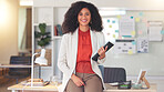 Young woman working on tablet and smiling. Young female is in an offie, sitting on a desk and busy working. She could be an accountant or lawyer speaking to a client or coworker.