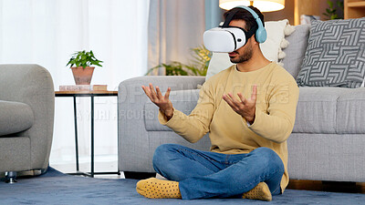 Male gamer using a VR headset to access the metaverse while gaming online at home. Young man enjoying video games with wireless headphones while entering an immersive 3D virtual reality experience
