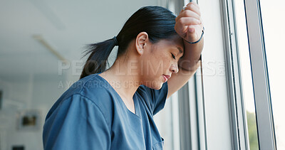 Healthcare nurse, stress and headache by window for working burnout, frustrated employee and tired asian woman in hospital. Doctor, pain and sad medical worker, anxiety or mental health depression