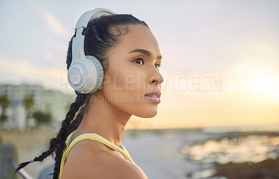 Buy stock photo Headphones, exercise music and woman at beach thinking about training, exercising or workout. Sports, fitness and female athlete streaming radio, podcast or audio after running at sunset by ocean.