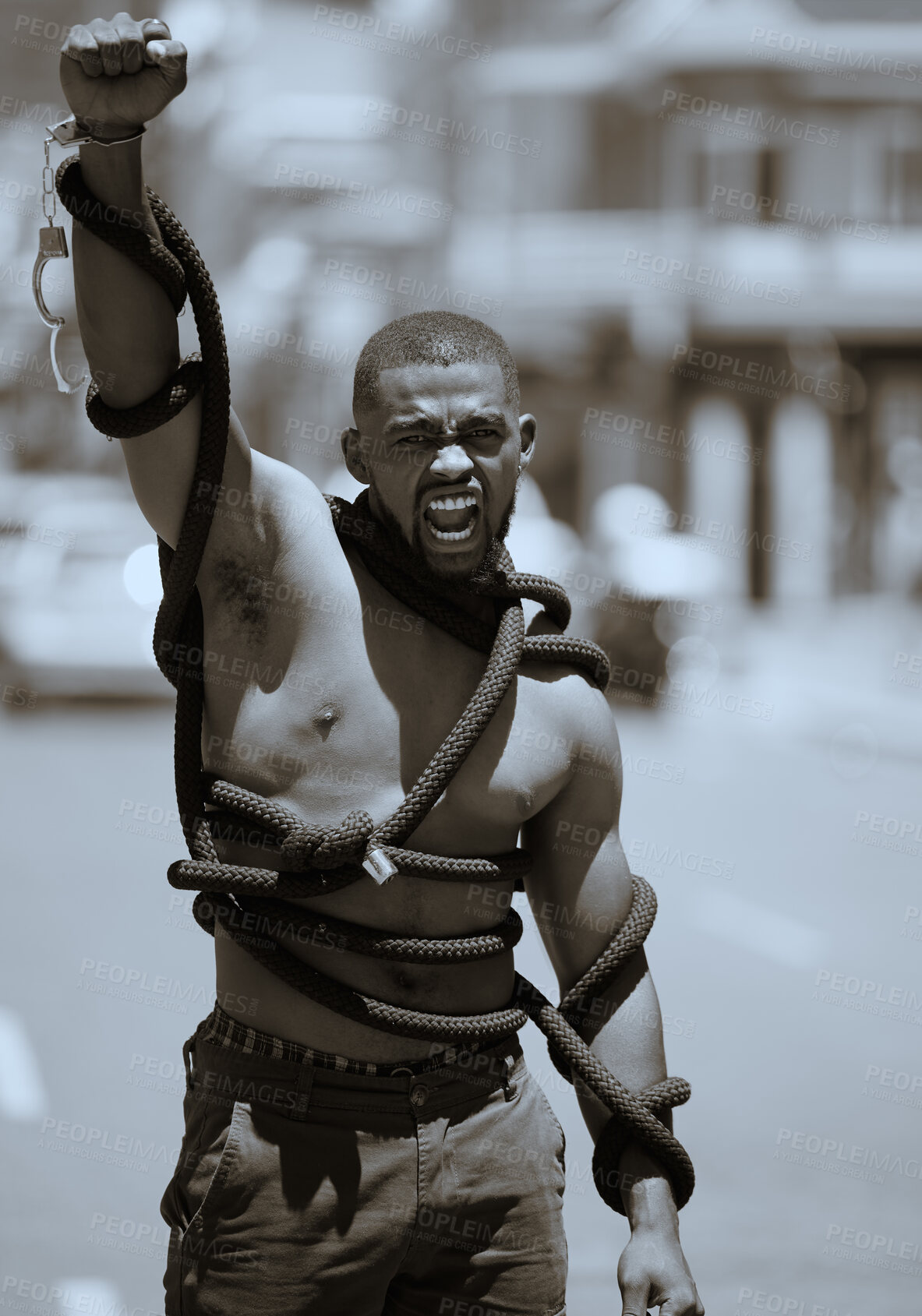 Buy stock photo Protest, fist and man in rope and handcuffs in city protesting against discrimination, oppression or slavery and racism. Black lives matter, justice and angry male in street fighting for human rights