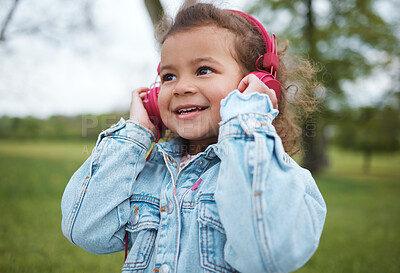 Buy stock photo Music, smile and baby in a park with headphones, radio freedom and streaming audio in Portugal. Podcast, happy and face of a girl child listening to a song for happiness, joy and cheerful in nature