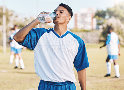 Buy stock photo Drinking water, break and soccer player on a sports field resting after match or competition on a sunny day. Man, athlete and sportsman refreshing during a game happy and smiling for due to fitness