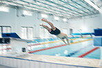 Swimming, action and man diving in pool for training, exercise and workout for competition at gym. Fitness, sports and motion blur of professional male athlete for dive, jumping and triathlon race