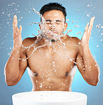 Water splash, facial and man in studio for skincare, wellness and grooming on blue background. Cleaning, beauty and moisture by Mexican model relax with luxury, routine and face treatment isolated