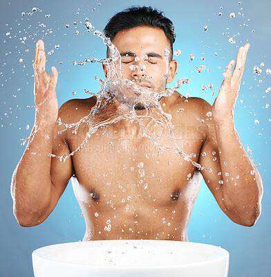 Buy stock photo Water splash, facial and man in studio for skincare, wellness and grooming on blue background. Cleaning, beauty and moisture by Mexican model relax with luxury, routine and face treatment isolated