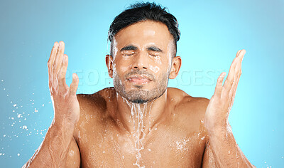 Buy stock photo Water splash, face and man in studio for skincare, wellness and grooming on blue background. Cleaning, beauty and facial by Mexican model relax with luxury, routine and moisture while isolated
