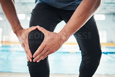 Buy stock photo Hands, knee injury and swim instructor holding his joint in pain with a swimming pool in the background of a gym. Fitness, coach or anatomy with a sports man suffering from a sore leg during exercise