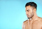 Water splash, shower and man in studio for skincare, wellness and grooming on blue background. Cleaning, beauty and moisture by Mexican model relax with luxury, routine and body care while isolated