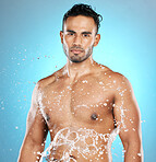 Portrait, splash and beauty, skin and skincare man cleaning his body, muscle and topless. Water, male and wellness model with moisture, cosmetic and hydration isolated in studio blue background