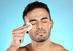 Man, cotton and man in studio for skincare, wellness and cleaning while grooming on blue background. Faical, pad and male skin model relax with luxury, cosmetics and product, hygiene and isolated