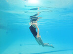 Swimming, fitness and sports with a woman floating in a pool for cardio or endurance exercise. Water, swimwear and health with a female swimmer during an aqua workout or competitive watersports game