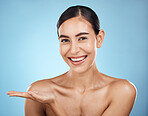 Portrait, beauty skincare and woman with product placement in studio isolated on a blue background. Face makeup, cosmetics and female model with marketing, advertising or branding space for mockup.