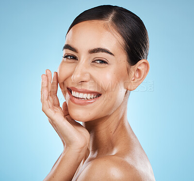 Buy stock photo Portrait, smile and skincare with a model woman in studio on a blue background for natural beauty. Face, skin and cosmetics with an attractive young female posing to promote a luxury product