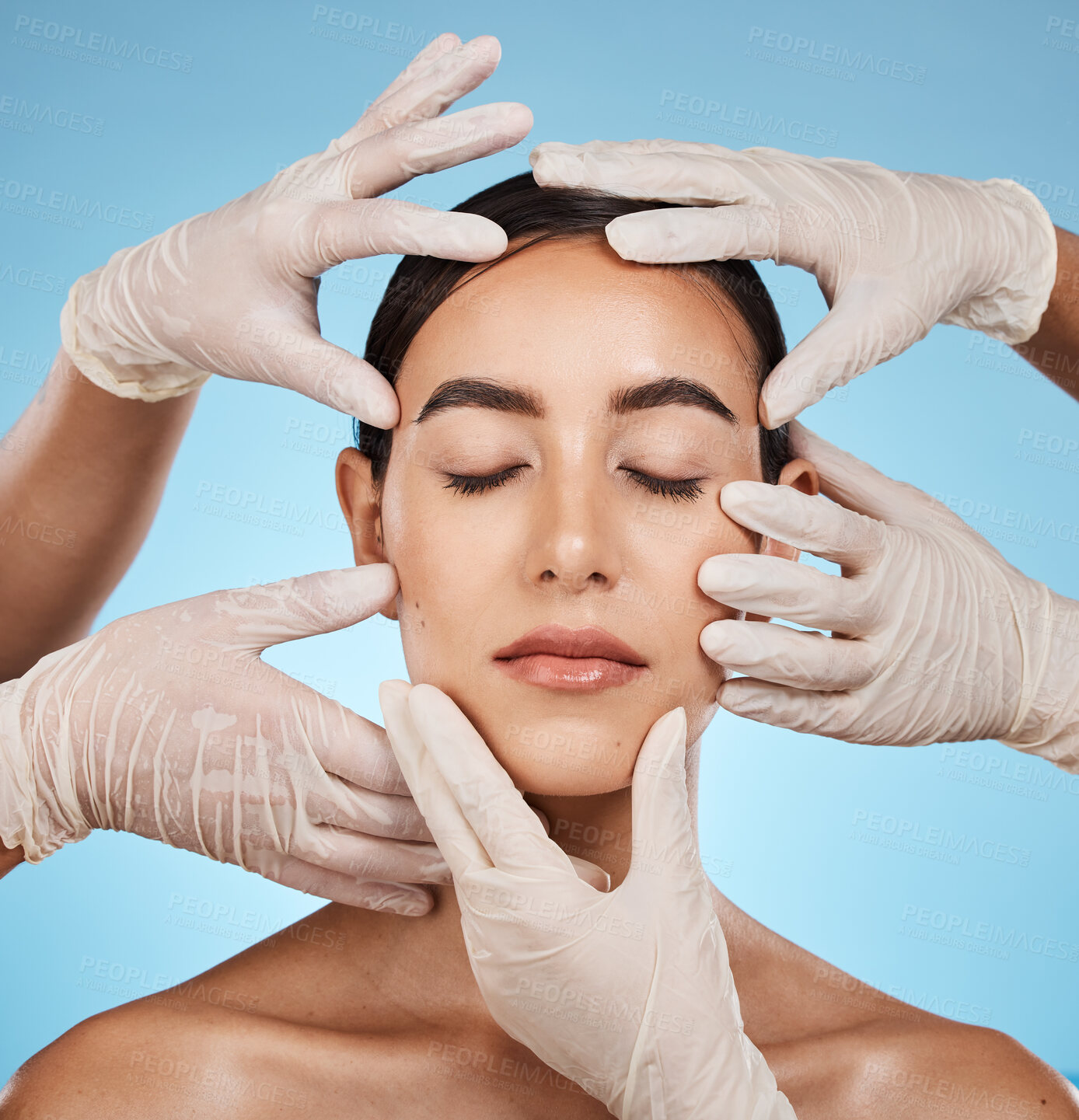 Buy stock photo Plastic surgery, beauty and hands on the face of a woman isolated on a blue background in a studio. Feeling, skincare and doctors touching a model for a botox, cosmetics or dermatology consultation