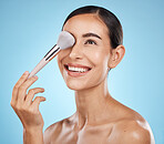 Face, beauty and makeup brush of woman in studio isolated on a blue background. Thinking, facial treatment and  skincare aesthetic of happy female model with tools for foundation, powder or cosmetics