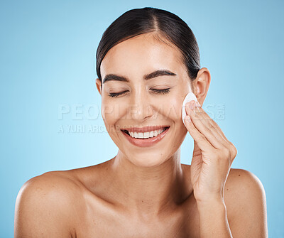 Buy stock photo Skincare, cotton pad and woman in a studio with a cosmetic, natural and facial treatment. Self care, beauty and happy female model with a healthy face or skin routine isolated by a blue background.