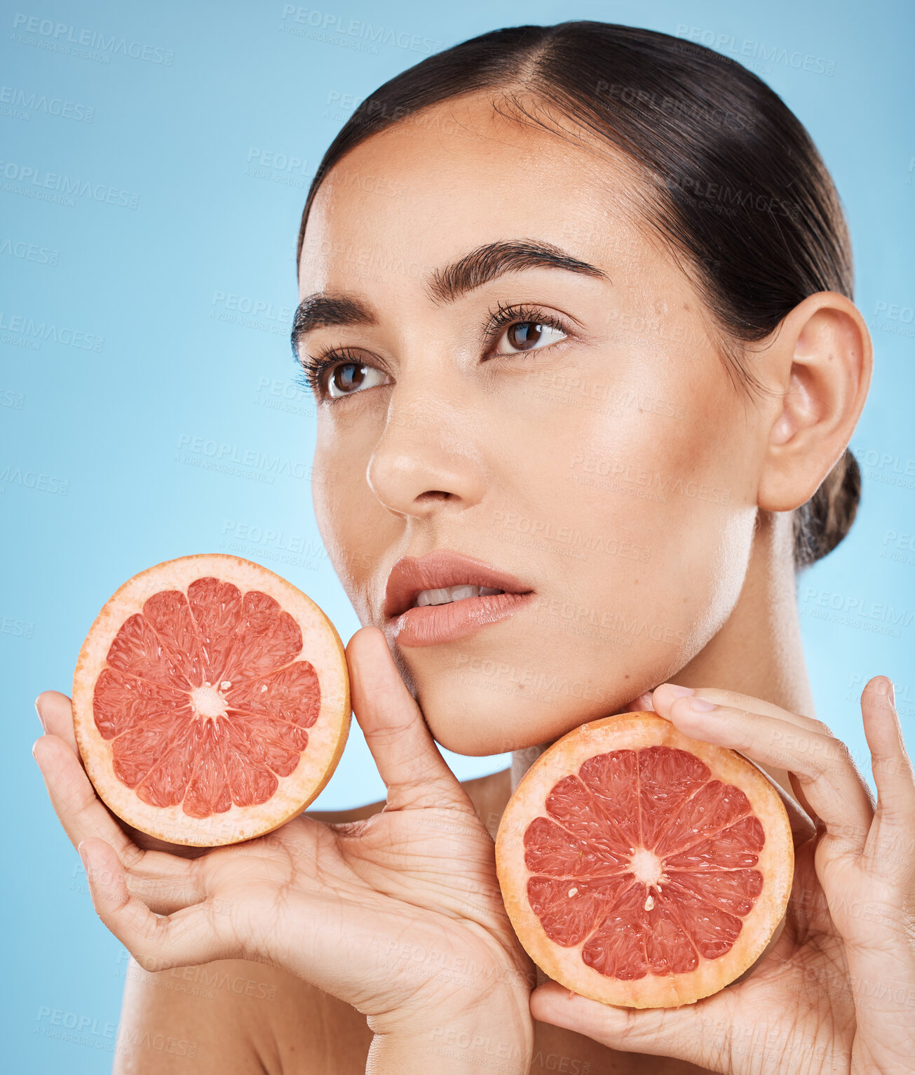 Buy stock photo Face, beauty and skincare of woman with grapefruit in studio isolated on a blue background. Organic cosmetics, food and  female model thinking about fruits for nutrition, healthy diet or vitamin c.