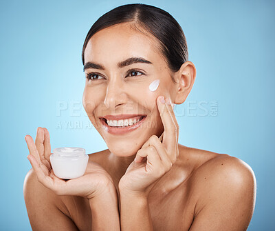Buy stock photo Face, cream and skincare product of woman in studio isolated on a blue background. Cosmetics, aesthetics and happy female model thinking about lotion, creme or moisturizer for beauty and wellness.