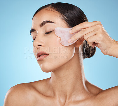 Buy stock photo Skin care, facial massage and beauty woman with gua sha for dermatology, cosmetics and wellness. Young model person with natural stone or spa face product to relax and glow on blue background
