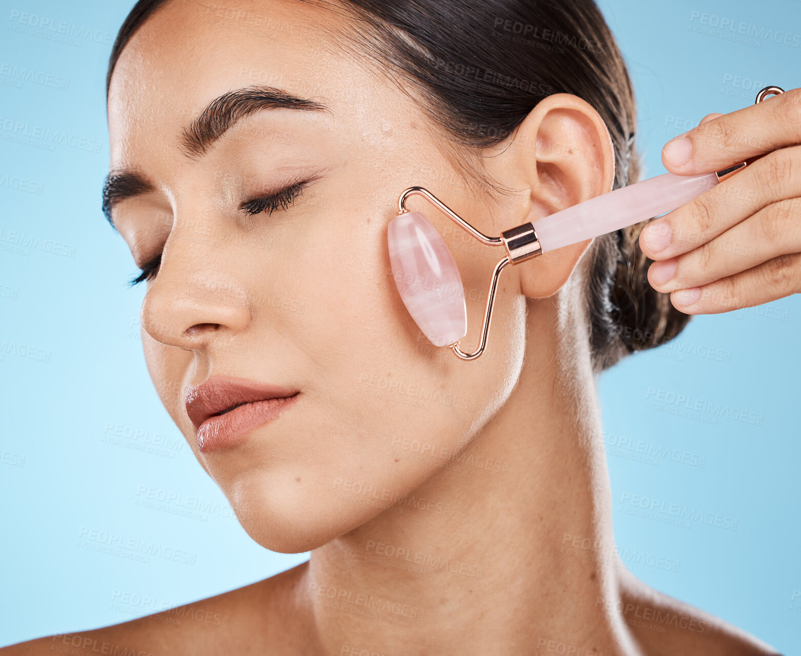 Buy stock photo Skin care, face roller and beauty woman with facial massage for dermatology, cosmetic and wellness. Young aesthetic model person for natural rose quartz spa product to relax on blue background