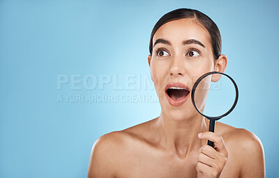 Buy stock photo Woman, face and surprise with magnifying glass, beauty and acne with skin problem isolated on blue background. Skincare cosmetics, wow and facial inspection, mockup space and dermatology in studio