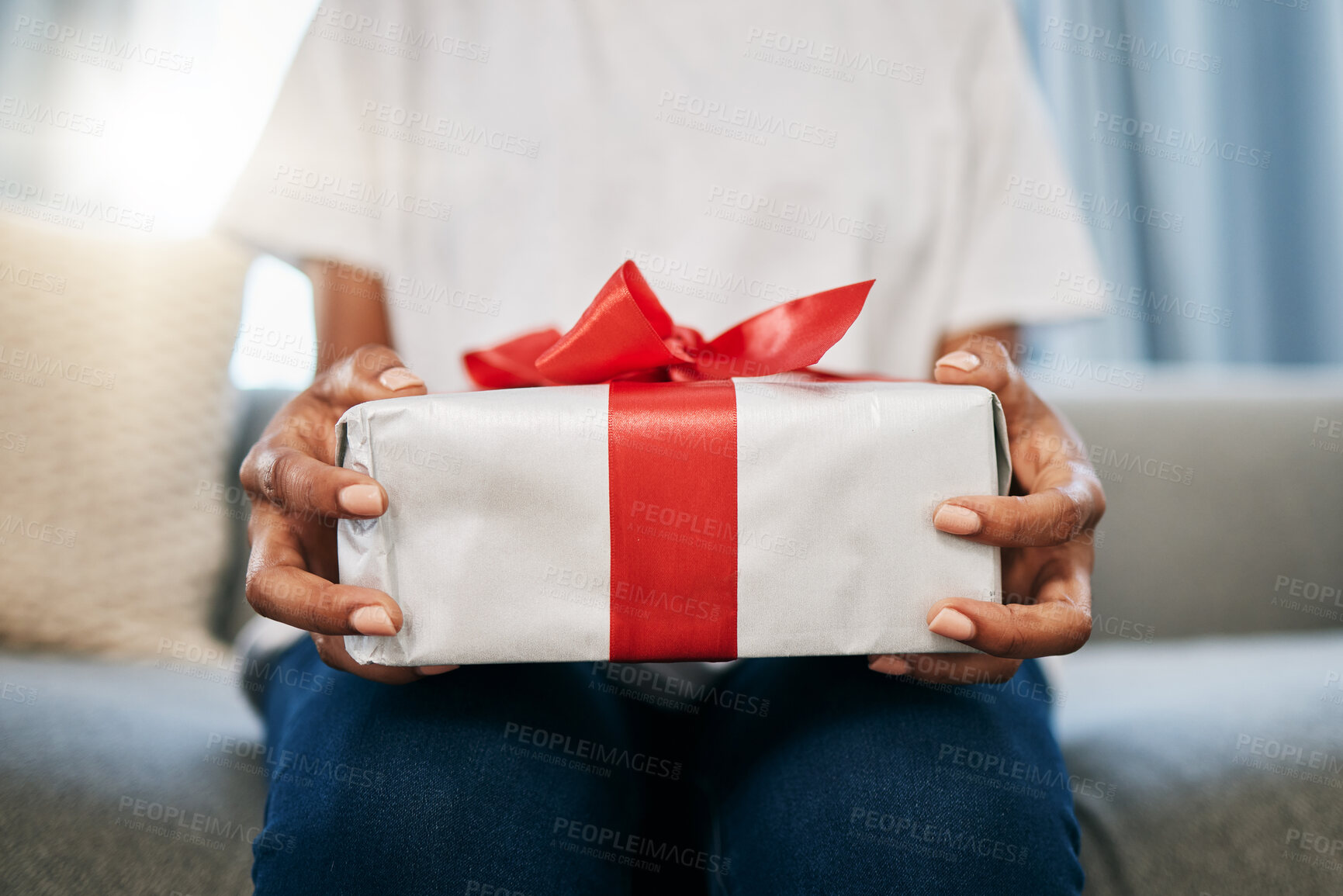 Buy stock photo Box, gift and woman on a sofa in the living room with a giving gesture for celebration or event. Bow, wrapping paper and African female with a present for christmas, birthday or holidays in a house.