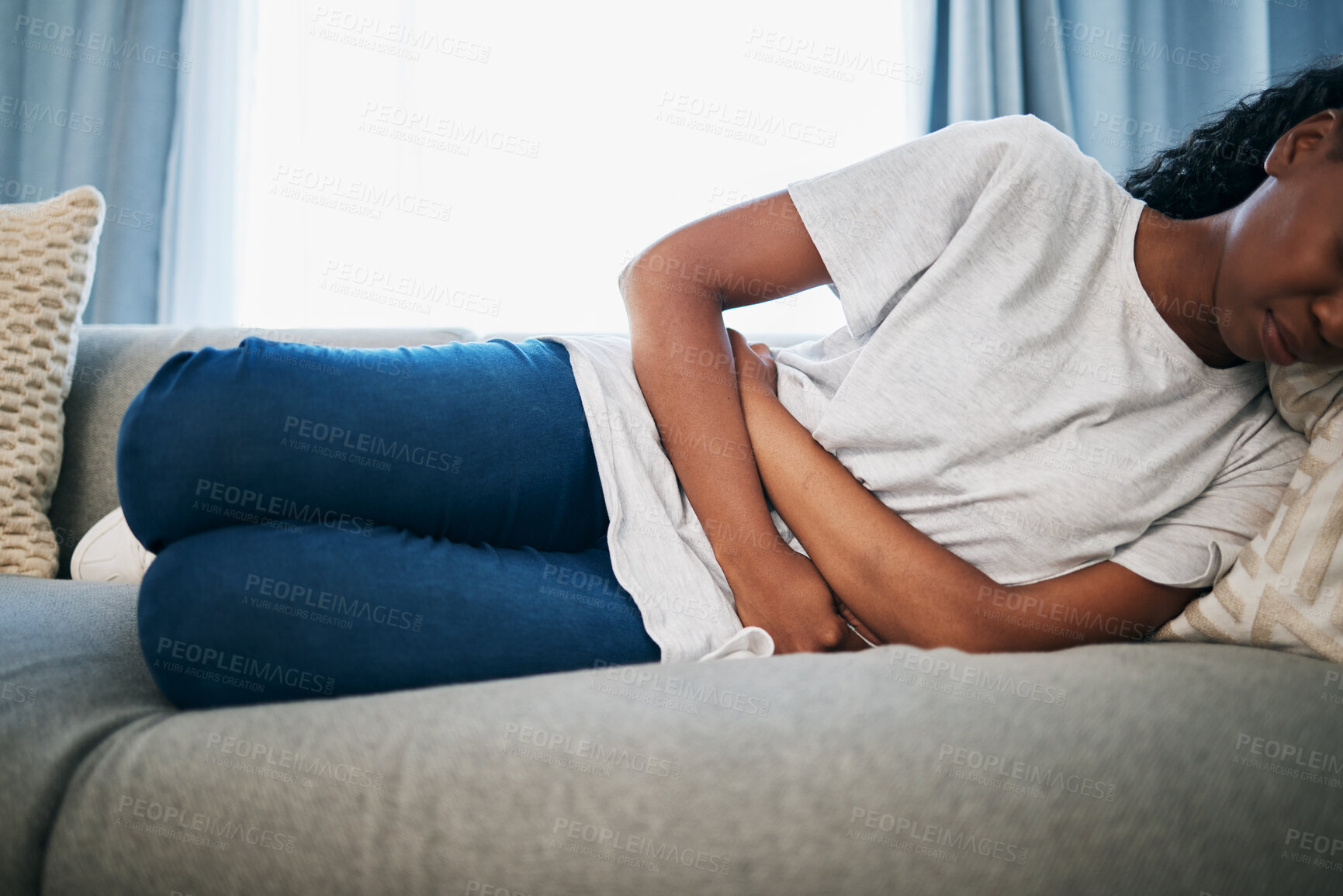 Buy stock photo Period, stomach ache and black woman with pain on sofa holding belly from sickness, cramps and digestion. Menstruation, endometriosis and girl on couch with menstrual problem, pms and bloated abdomen