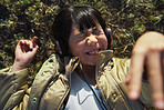 Funny little asian girl wearing headphones lying on grass laughing having fun listening to music in park