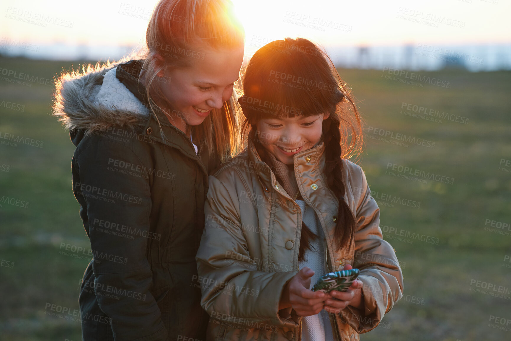 Buy stock photo Phone, kids and friends at park on social media, internet browsing or web scrolling. Technology, smartphone and happy children or girls with mobile for texting, streaming or gaming outdoors at sunset