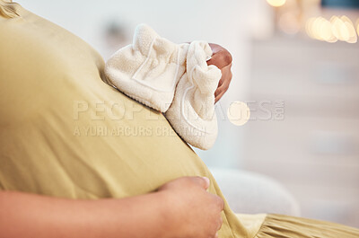 Buy stock photo Black woman, pregnancy stomach and closeup of shoes on home living room sofa, hands and excited for baby. Future mother relax, couch and pregnant in lounge by blurred background in house with hope