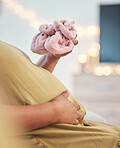 Baby shoes, pregnant stomach and woman hands with baby clothes holding her abdomen. Mother, mom love and gratitude of a new mama with family care for pregnancy in a living room lounge with slippers