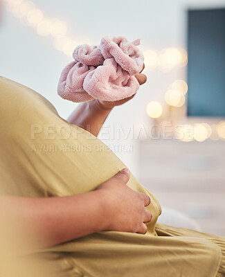 Buy stock photo Baby shoes, pregnant stomach and woman hands with baby clothes holding her abdomen. Mother, mom love and gratitude of a new mama with family care for pregnancy in a living room lounge with slippers