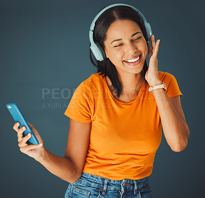 Buy stock photo Music, headphones and woman streaming a song on phone or mobile app isolated against a studio background. Fun, sound and female enjoying and listening to podcast, radio or audio smiling and happy