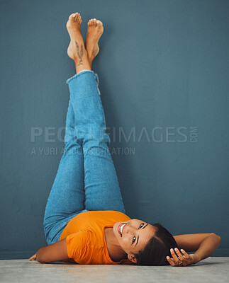 Buy stock photo Woman on floor, smile on face with legs up on wall background and creative pose in studio. Teal copy space, young model laying on ground, portrait of happy person alone and body relaxing aesthetic