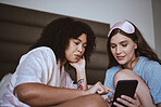 Phone, sleepover and friends in bed talking, bonding and networking on social media, mobile app or internet. Fun, technology and women browsing on a website with a cellphone in a bedroom at home.