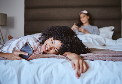Buy stock photo Relax, smile and phone with black woman at sleepover for communication, internet or contact. Happy, online dating and texting with girl and friends in bedroom with technology, digital or social media