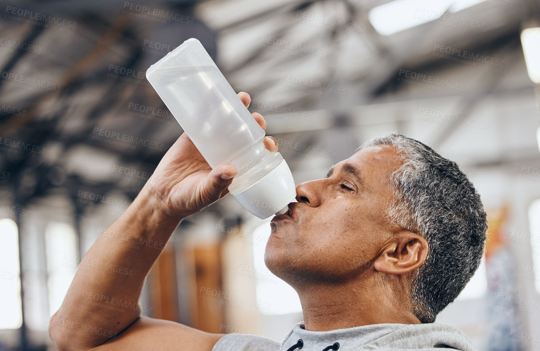 Buy stock photo Man, fitness and drinking water bottle for hydration after workout, exercise or cardio training indoors. Sporty male staying hydrated for healthy endurance, recovery or thirst from sports exercising