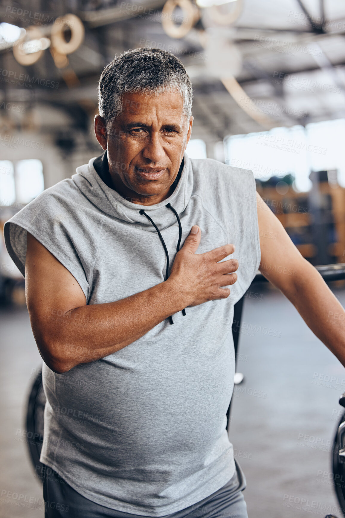 Buy stock photo Fitness, gym and old man with pain in chest, medical emergency during workout at sports studio. Exercise, health and wellness, stress and tired senior person with hand on heart muscle while training.