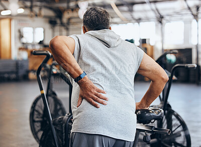 Buy stock photo Sports, gym and injury, old man with back pain, emergency during workout at fitness studio. Health, wellness and inflammation, senior person with hand on muscle cramps while training on exercise bike