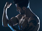 Muscle, showing and man with arms in the dark for fitness isolated on a studio background. Exercise, training and muscular bodybuilder flexing a bicep for workout results, performance and progress