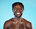 Water drops, skincare and black man isolated on blue background for face cleaning, body shower and skincare. Strong, beauty and happy model or person facial glow in studio headshot washing or hygiene