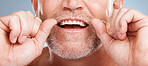 Closeup, floss and man with dental health, cleaning teeth and fresh breath against grey studio background. Male, gentleman and string for oral hygiene, wellness and morning routine for mouth grooming