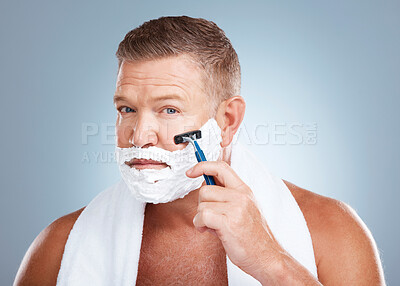 Buy stock photo Face, shaving cream and man with razor in studio isolated on a blue background for hair removal. Portrait, skincare and  mature male model with facial foam to shave for aesthetics, health or wellness